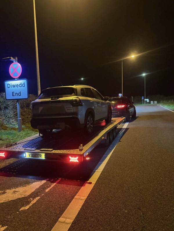 Suzuki S-Cross on the transporter at night beside a bilingual Welsh Diwedd End road sign